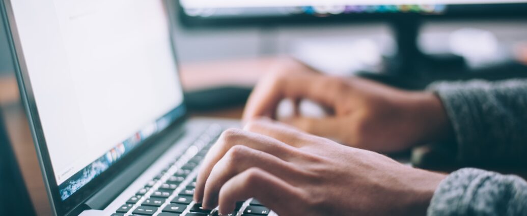 Hands typing on laptop keyboard