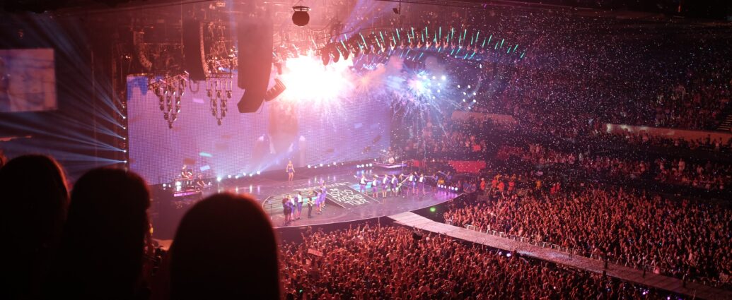 A photo from Taylor Swift's 1989 world tour. The stage lights are orange, blue and purple. Fans will be excited to see if she includes her track All Of The Girls You Loved Before on the setlist for her ongoing Eras tour.