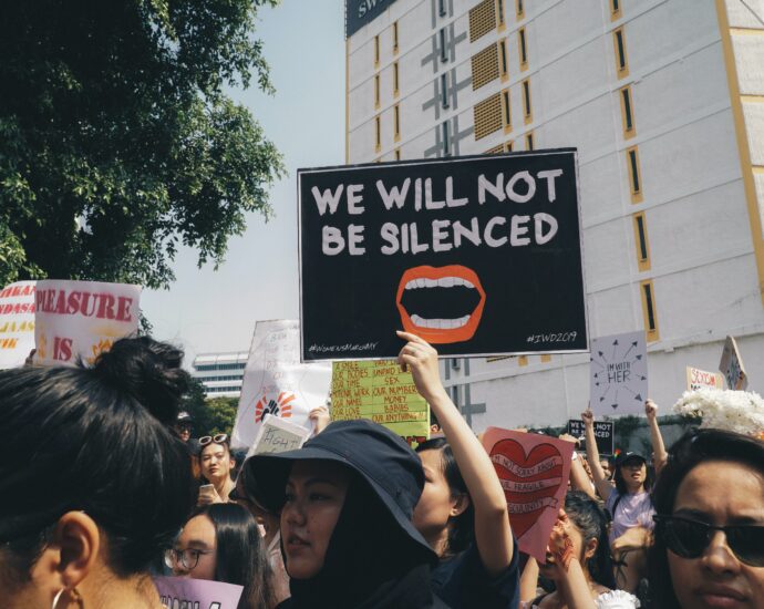 Image of a somebody holding up a sign at a women's rights protest saying "we will not be silenced"