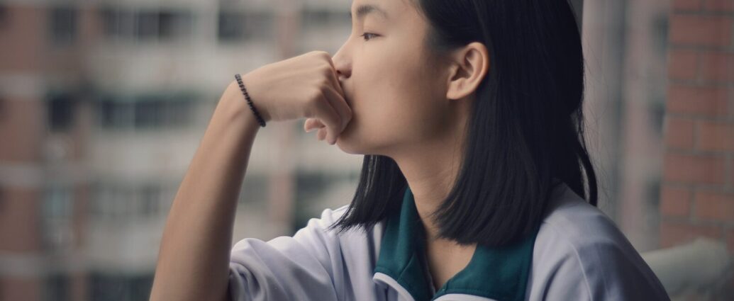 girl leaning on hand, staring out of window and overthinking