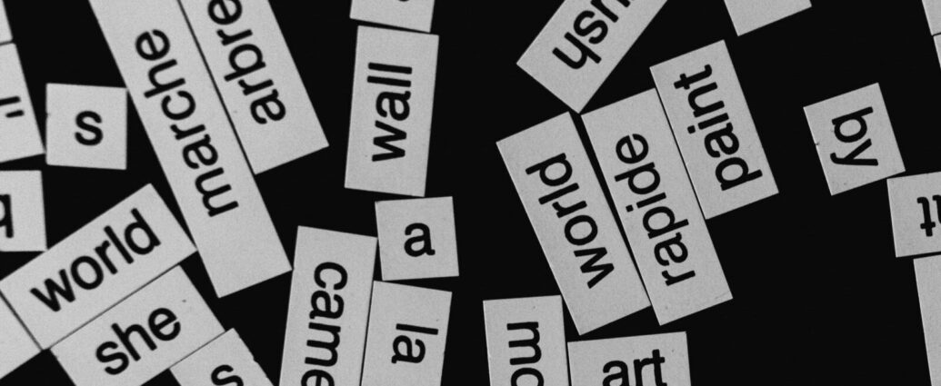 Image shows a black background with white stickers containing words in different languages