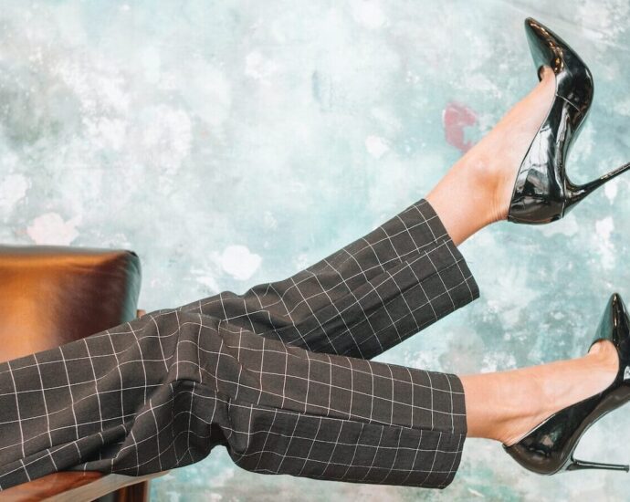A pair of legs wearing fashionable trousers and fancy high heel shoes.