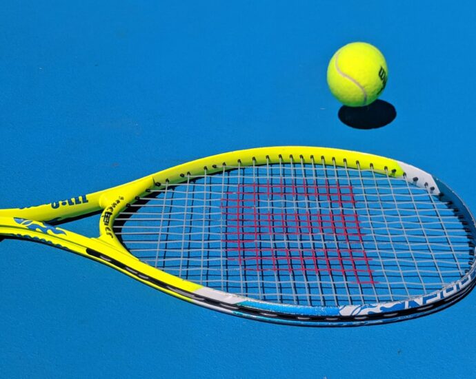 Tennis racket and ball on blue court