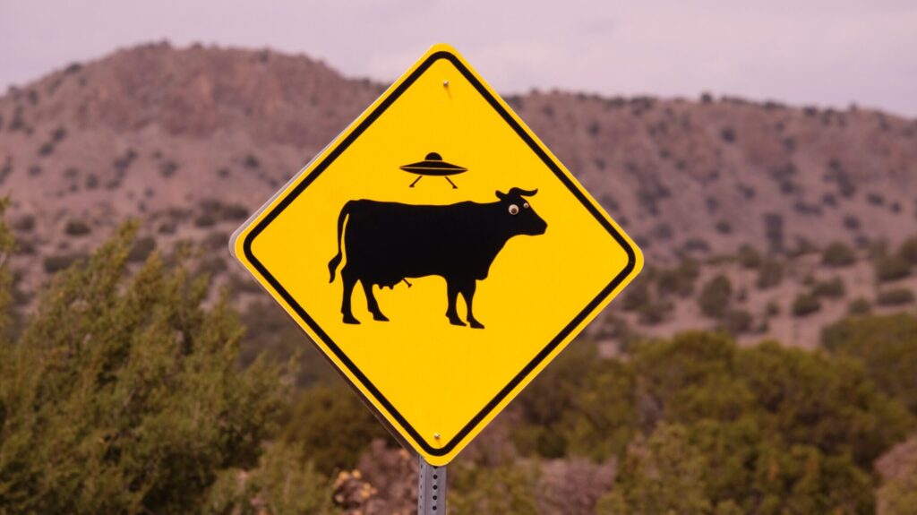 Road sign depicting a UFO abducting a cow.
