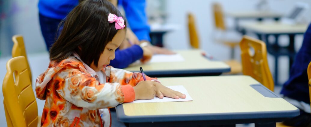 Little girl sitting at a school desk and writing.