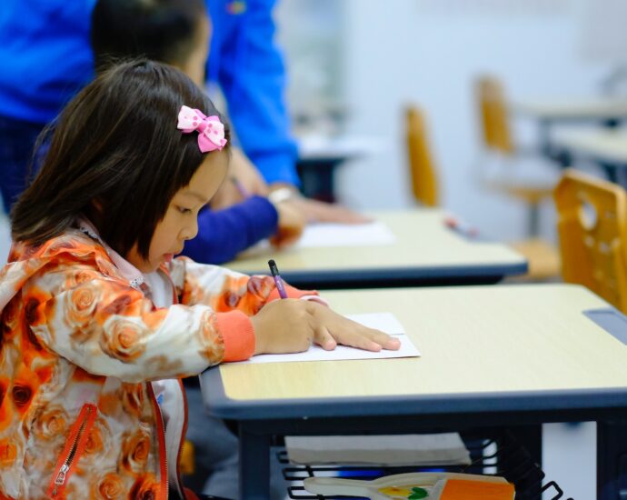 Little girl sitting at a school desk and writing.