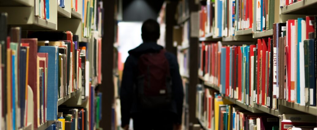A student standing in the aisles of a library.