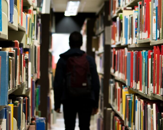 A student standing in the aisles of a library.