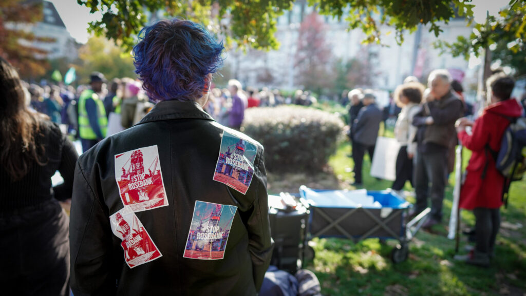 An activist with "Stop Rosebank" leaflets attached to the front and back of her jacket.