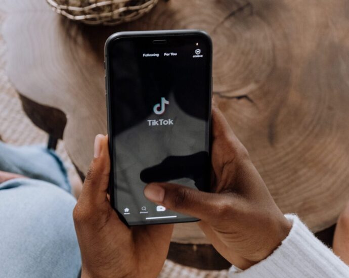 Someone holding a phone with TikTok open - TikTok is the hub of 'girlification'