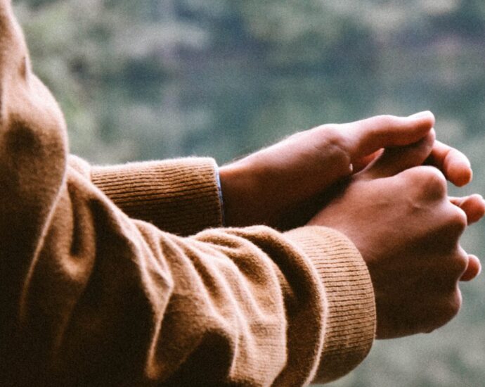Someone resting their hands on railing looking out onto a lake