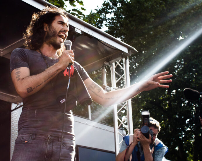 An image of Russell Brand speaking at an event.