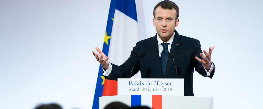 President Macron delivers a speech at a lectern.