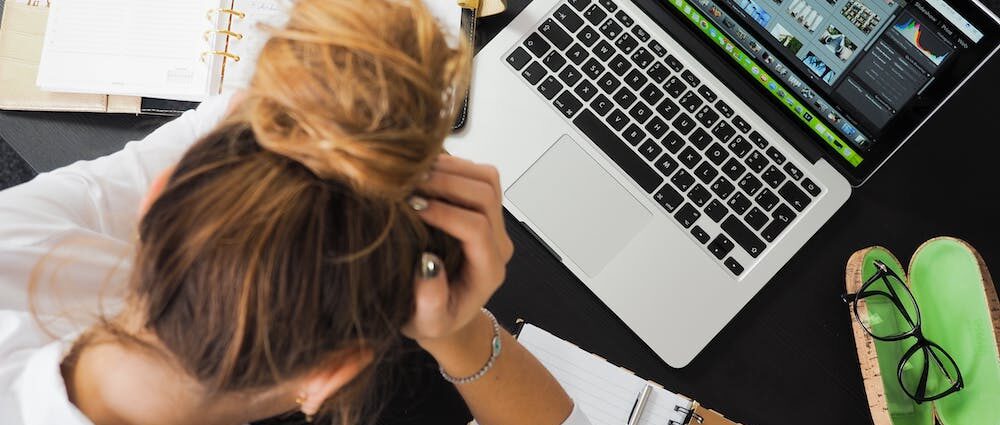 Woman with her head down sitting at laptop with writers block.