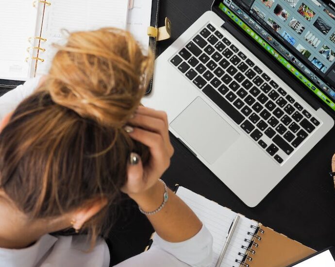 Woman with her head down sitting at laptop with writers block.