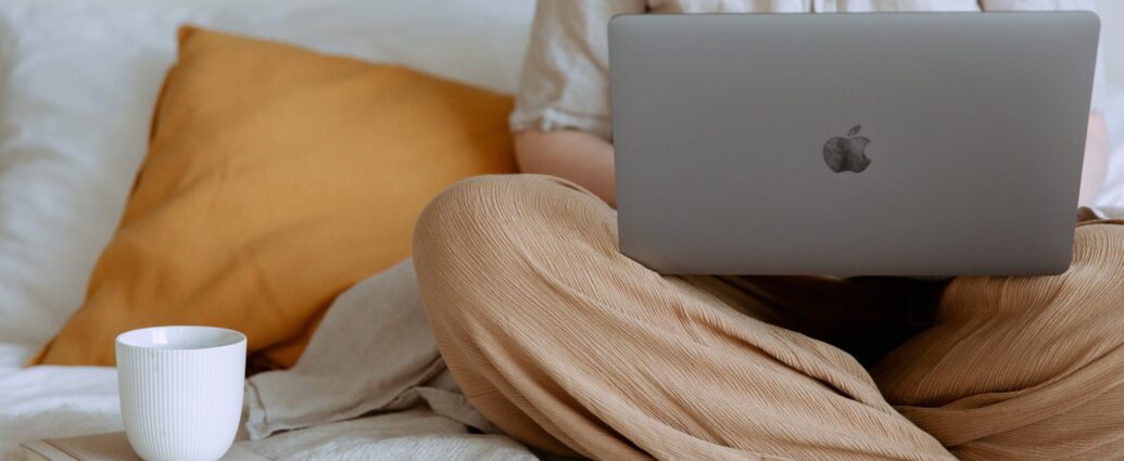 person sitting crossed legged on a bed with a laptop in their lap. My journalism journey.