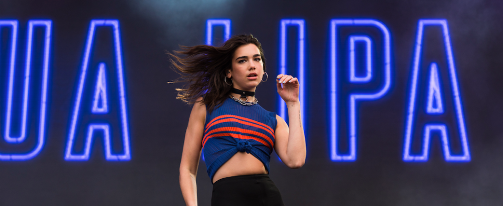 Dark haired young woman on stage back by neon lights.