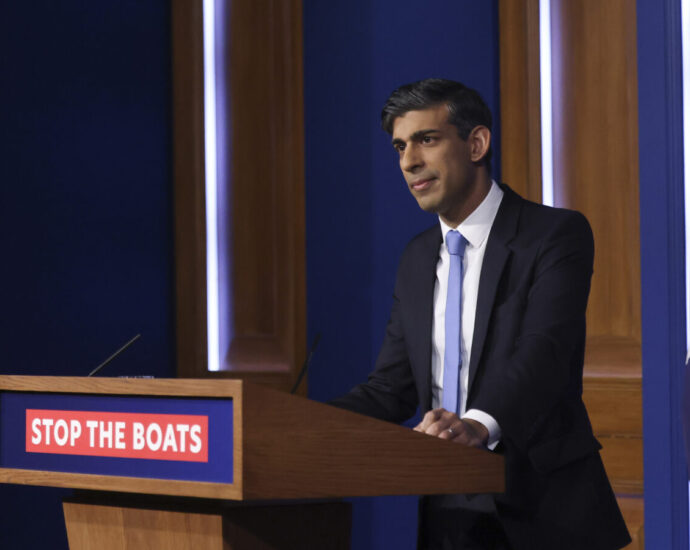UK Prime Minister Rishi Sunak behind a podium that says 'stop the boats'