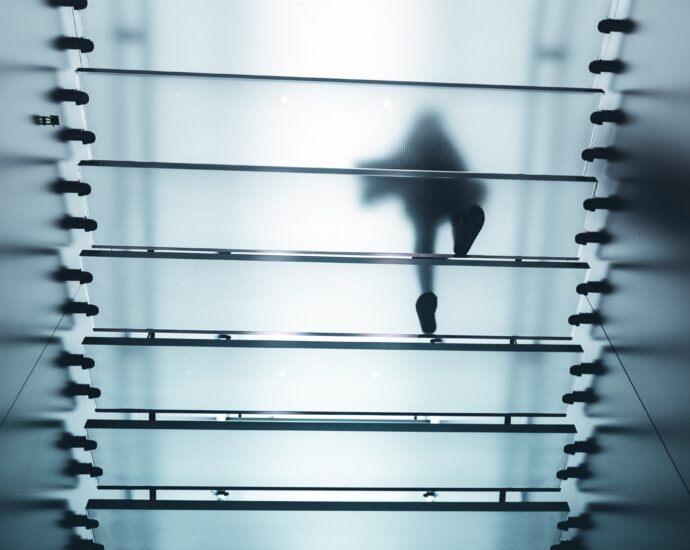 A figure walking above frosted glass stairs