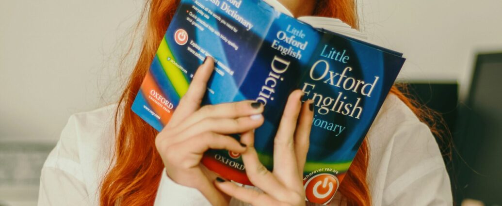 A woman holds an Oxford English Dictionary.