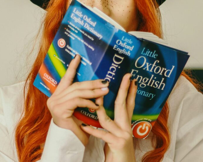 A woman holds an Oxford English Dictionary.