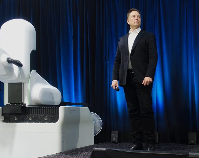 Elon Musk stands next to Neuralink robot device
