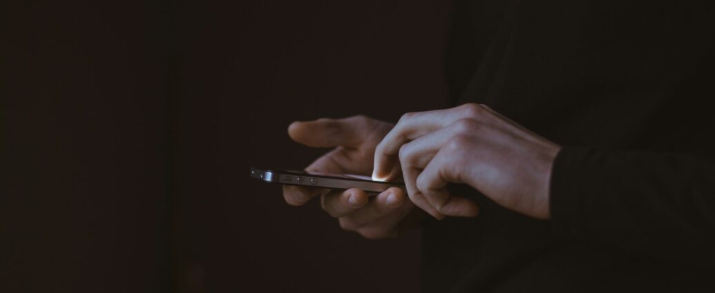 Silhouette of person holding phone with illuminated screen.