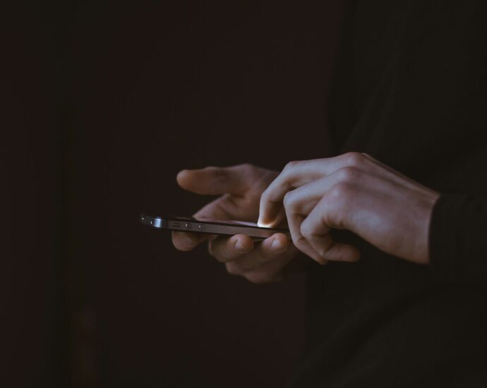 Silhouette of person holding phone with illuminated screen.