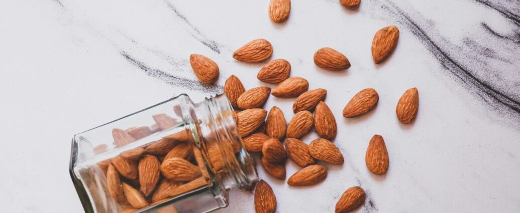 Brown almonds on white marble surface.