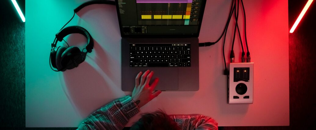 A person sitting in front of a desk with a laptop and headphones working on media leaks