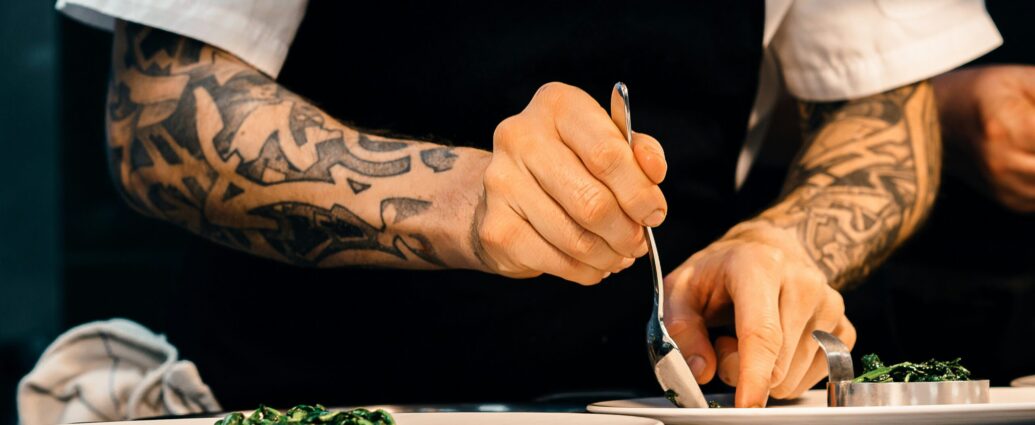 tattooed chef's arms plating up dish