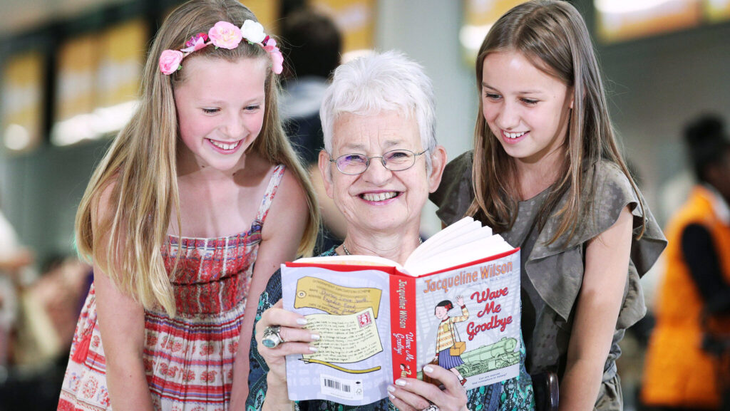 Jacqueline Wilson holding a book smiling