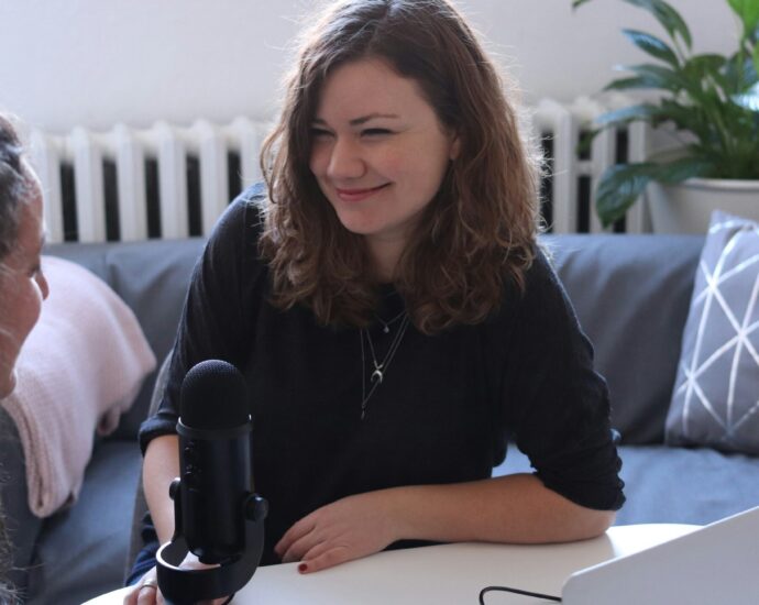 Journalist with a microphone smiles to an interviewee.