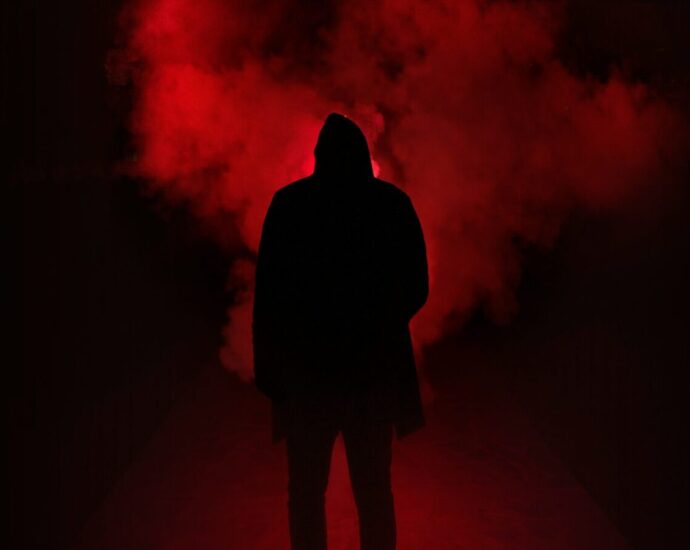 A shadowy figure stands in front of a red fog. Why are some of the "red-pilled" commentators of the "manosphere" women?