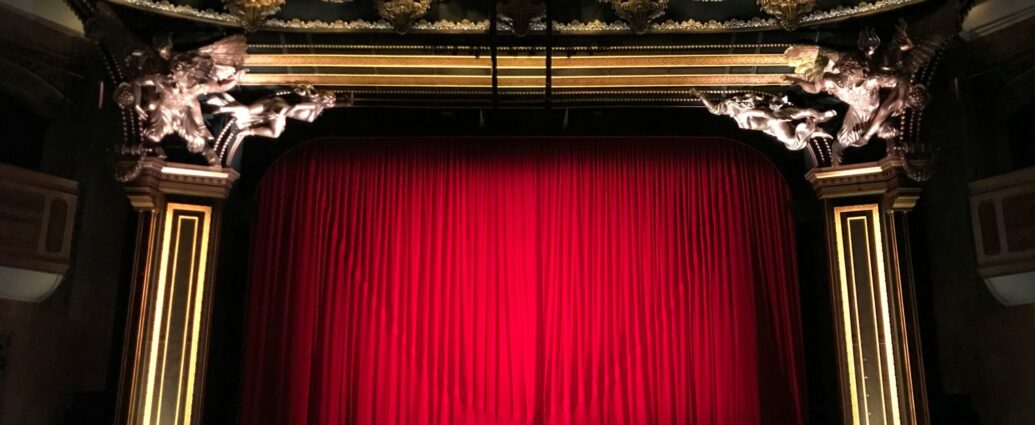 Image shows a closed red curtain on theatre stage - is the stage set for musical after musical?