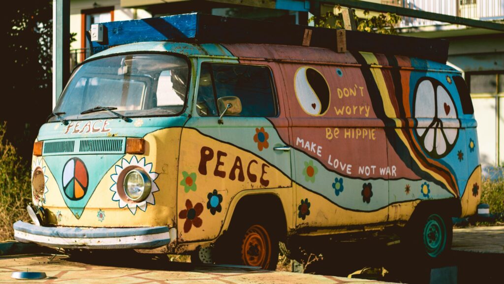 Blue and yellow Volkswagen hippie van with flowers and a peace symbol painted on