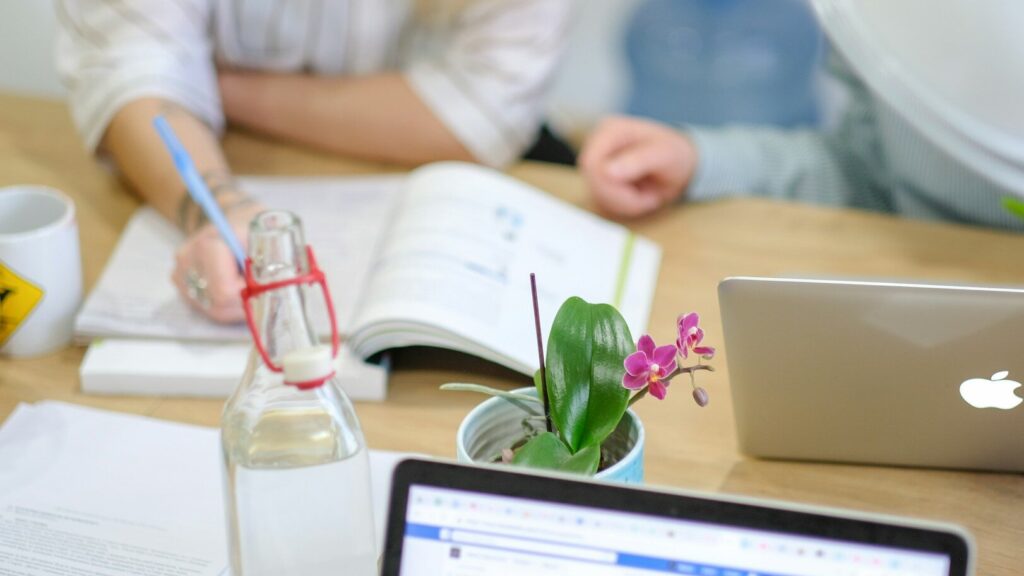 woman writing on printer paper on wooden table