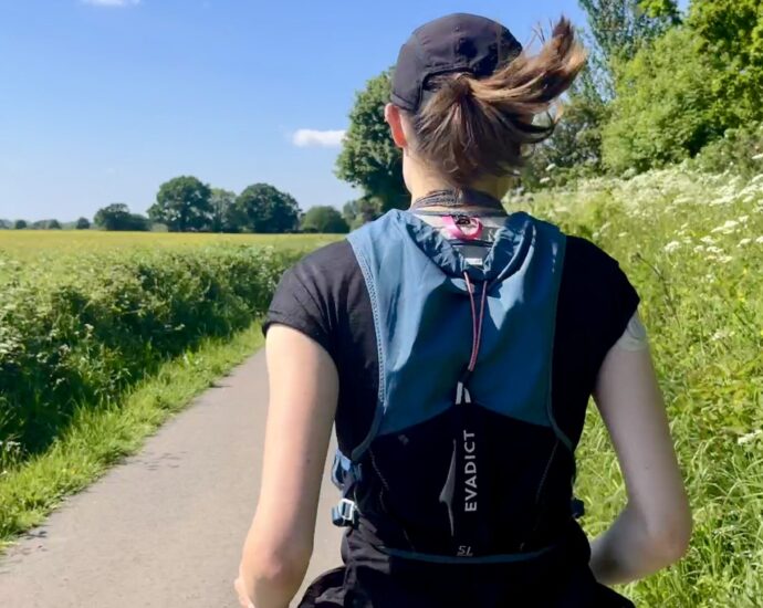 The back of a girl running with her hair in a ponytail, wearing a running vest as she tries Chi Running.