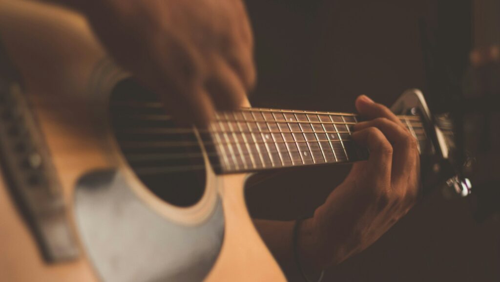 Individual playing the guitar. Representing A Complete Unknown