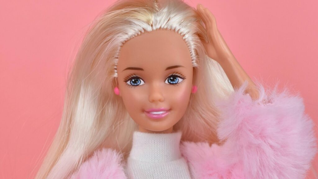 A blonde Barbie Doll wearing a pink jacket