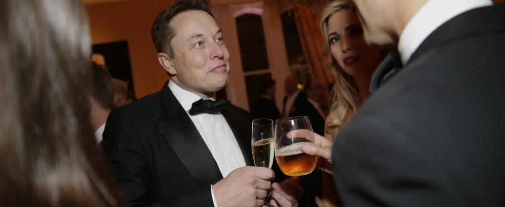 Photo of Elon Musk at an event, raising a drink towards another person