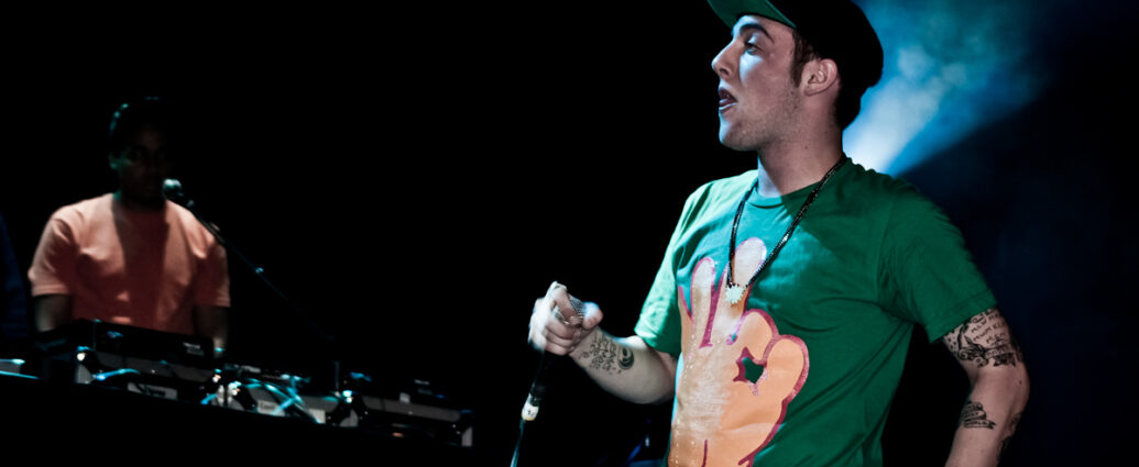 Artist and rapper Mac Miller performing at a concert on stage in green t-shirt. Promoting Balloonerism album