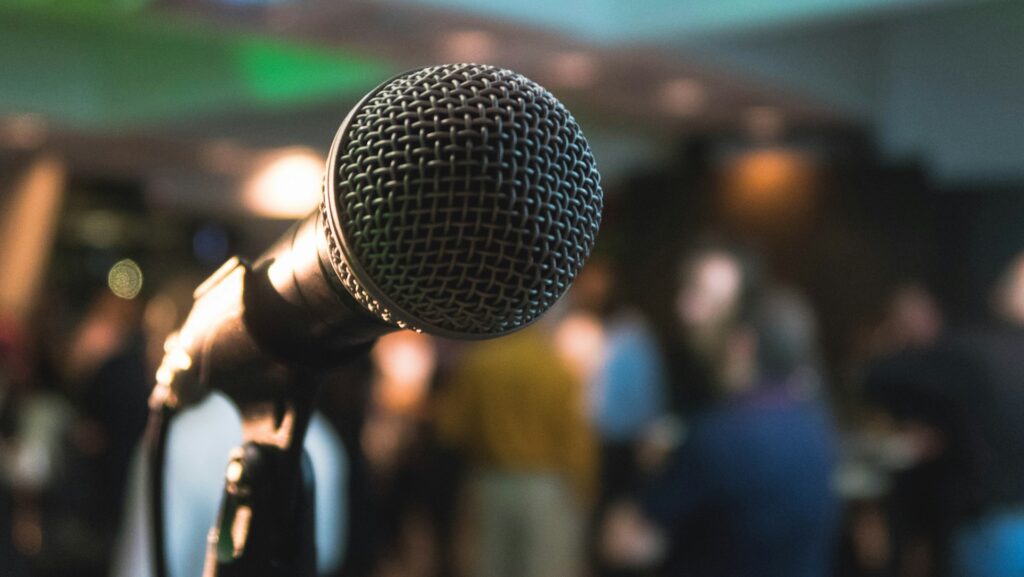 Microphone on stage with people blurred in the background.