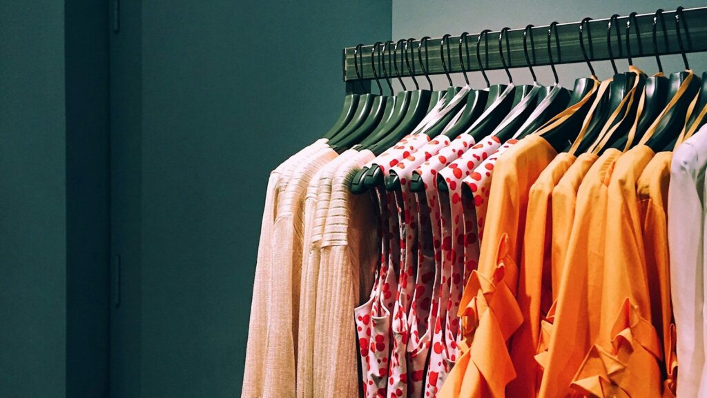 Orange and pink shirts hung on a clothing rail