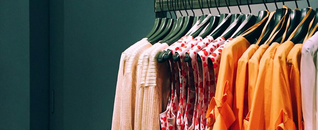 Orange and pink shirts hung on a clothing rail