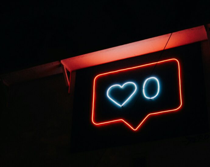 Neon sign depicting an outline of an Instagram 'like' social media symbol