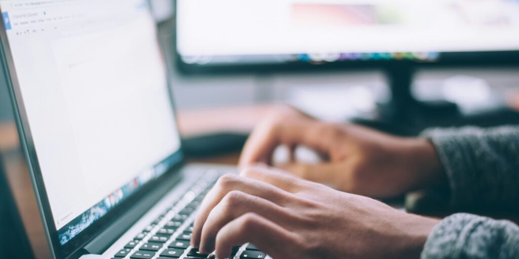 A person typing and doing research on a laptop.