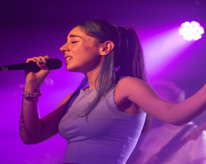 Samia singing in to a microphone with purple lighting in the background