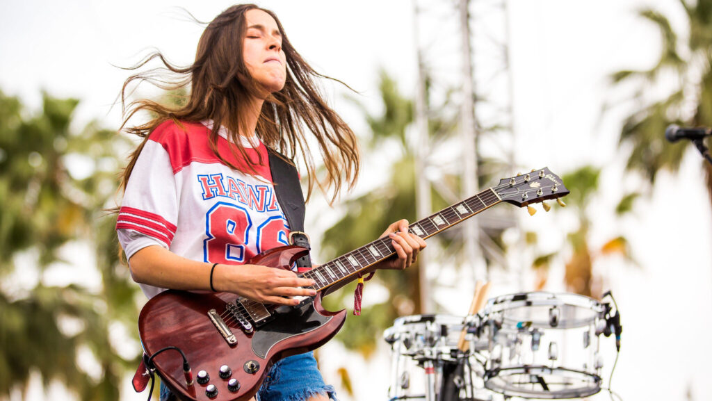 Danielle Haim playing guitar at Coachella Festival.
