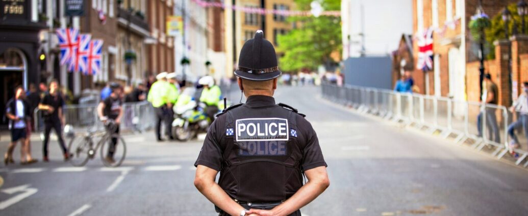Police officer standing in a community with his arms behind his back.
